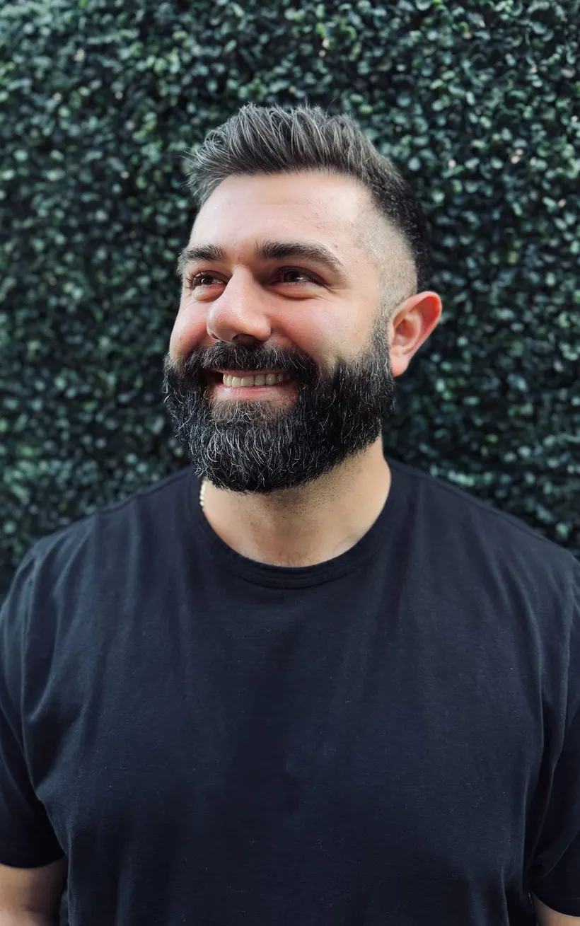 Joshua Palassis laughing, in a black t-shirt